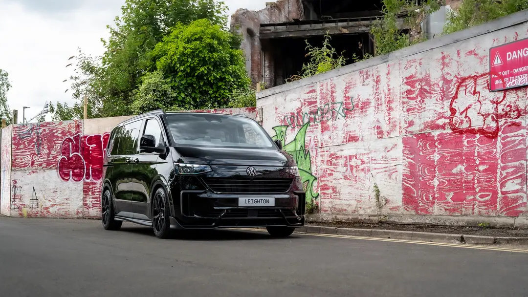 Black VW Transporter T7 kombi in front of a graffiti wall