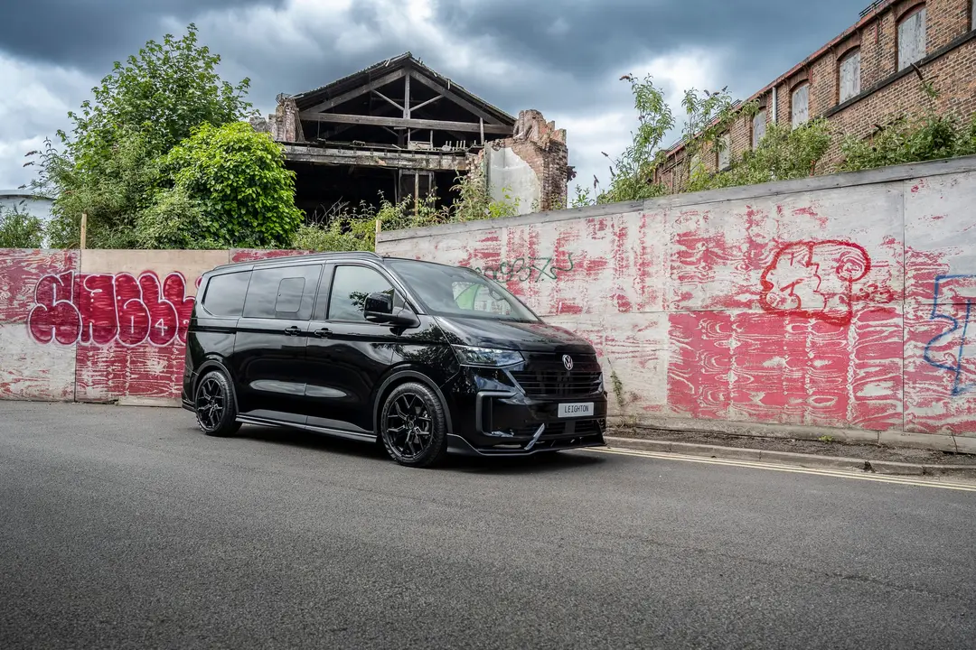 Black VW Transporter T7 kombi in front of a derelict building