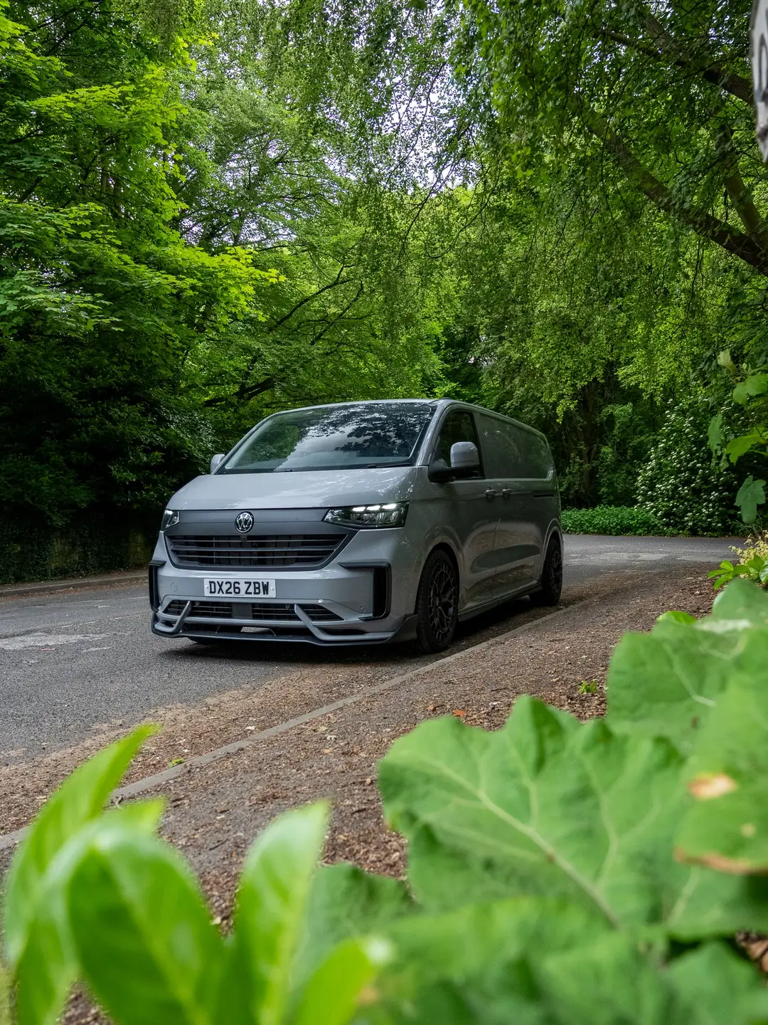 Grey VW Transporter T7 panel van on a woodland road